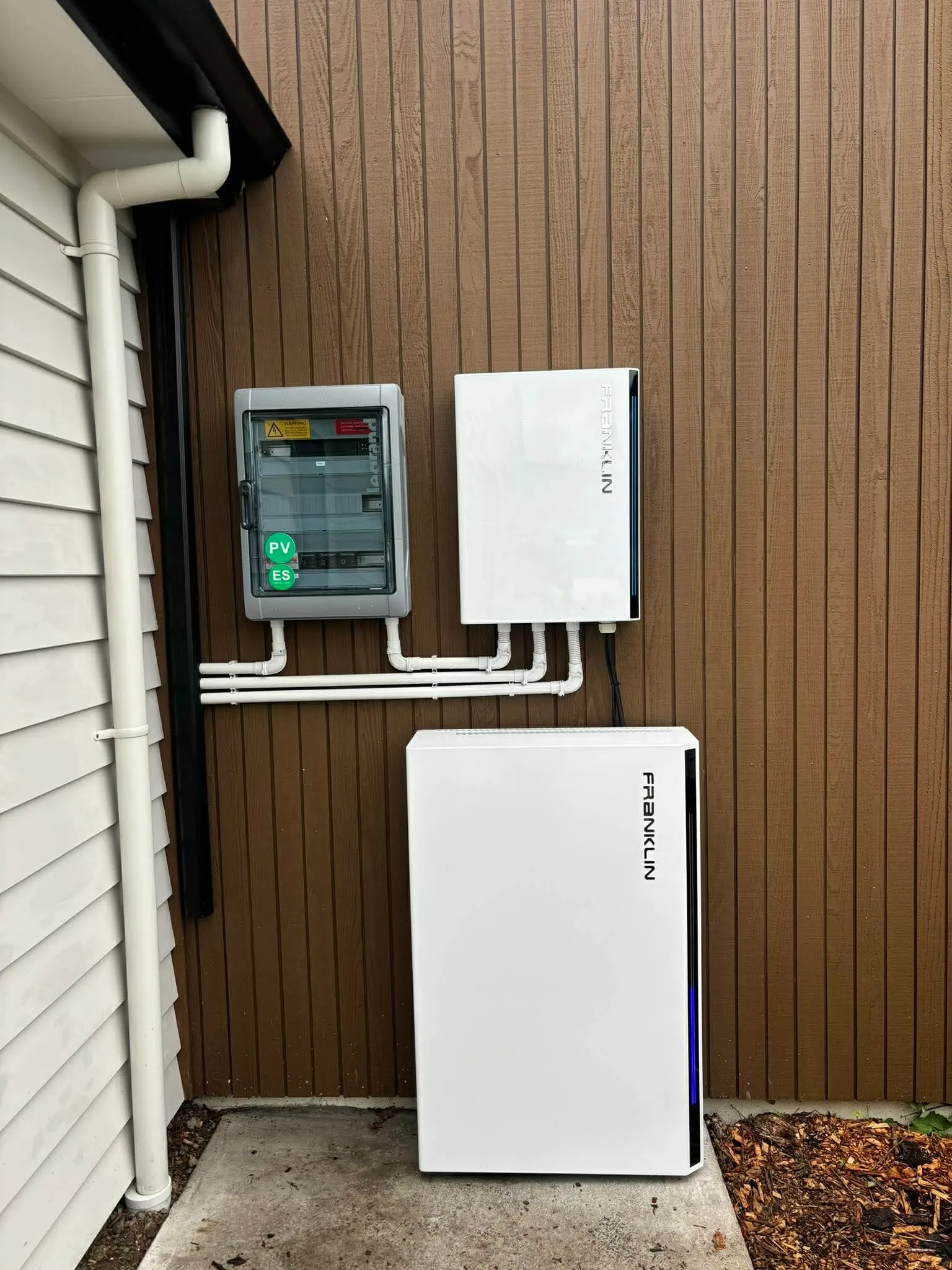 FranklinWH aPower battery and gateway mounted on a dark cedar wall