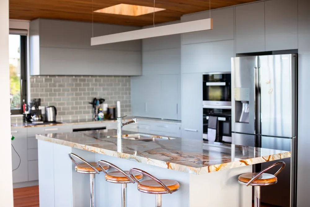 Modern Auckland kitchen with downlights and pendant lighting installed by Vital Energy