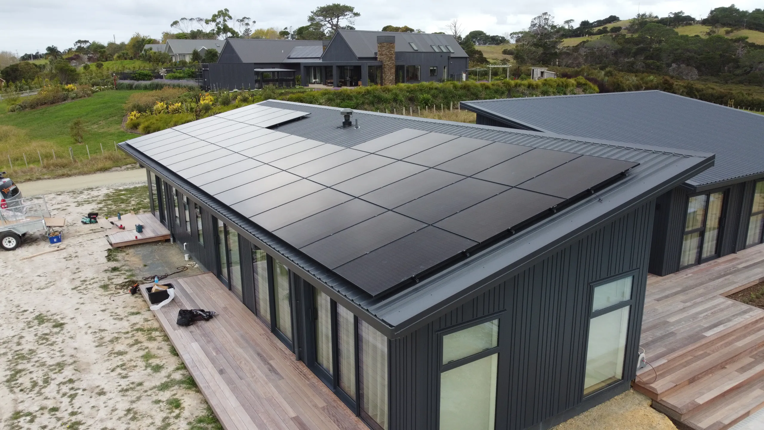 Full roof black solar array on a modern dark-clad Auckland home, drone view
