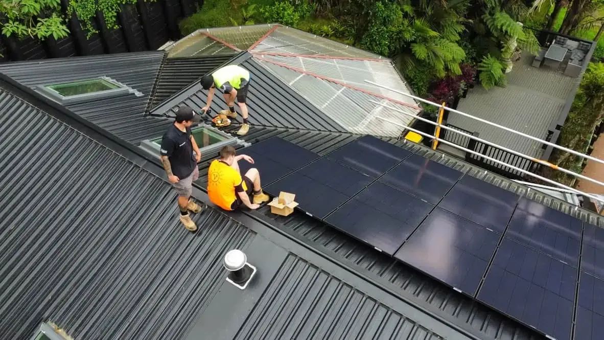 Vital Energy installers fitting solar panels on a long metal roof